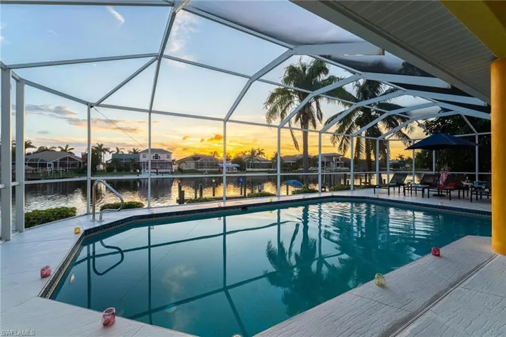 Pool at dusk with an outdoor pool and a sunroom