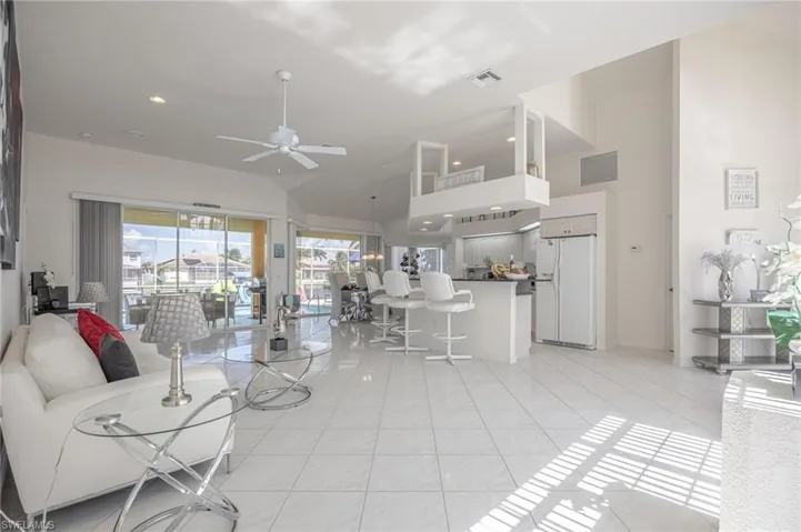 Living room with ceiling fan, recessed lighting, light tile patterned floors, and lofted ceiling
