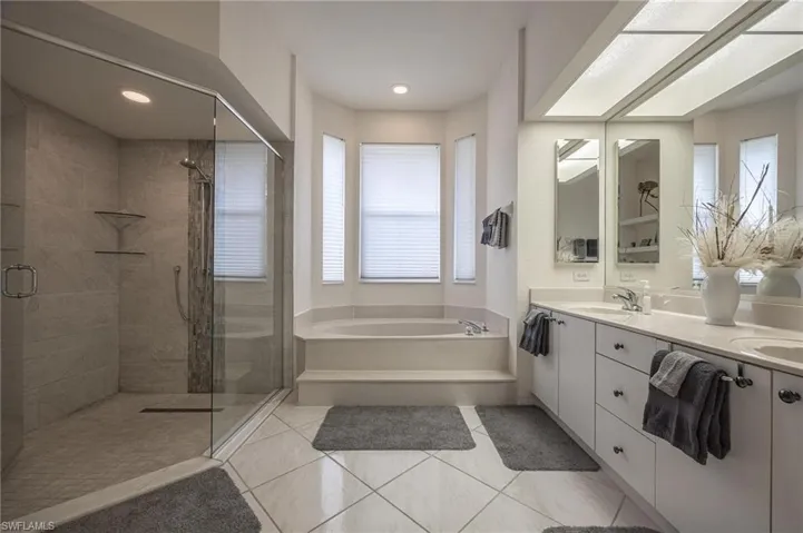 Full bathroom with double vanity, a stall shower, a bath, light tile patterned floors, and recessed lighting