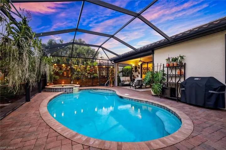 Pool at dusk featuring a sunroom, a grill, a lanai, a patio, and a pool with connected hot tub