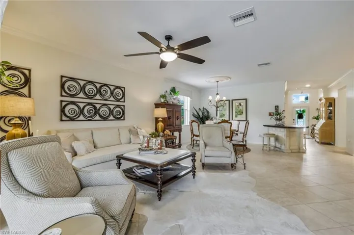 Living room featuring ornamental molding, ceiling fan, light tile patterned floors, and a chandelier