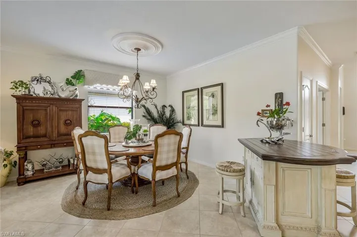 Dining room with ornamental molding, light tile patterned floors, and a chandelier