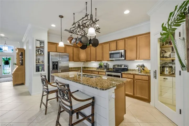 Kitchen featuring dark stone countertops, brown cabinets, light tile patterned flooring, a breakfast bar, and ornamental molding