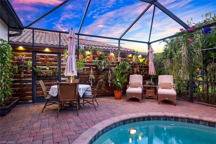 Pool at dusk with glass enclosure, a patio area, an outdoor pool, and a sunroom