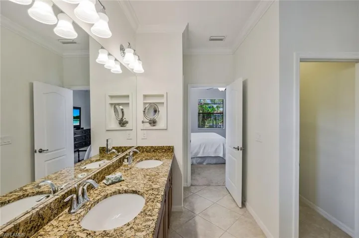 Bathroom featuring double vanity, ornamental molding, ensuite bathroom, and light tile patterned floors
