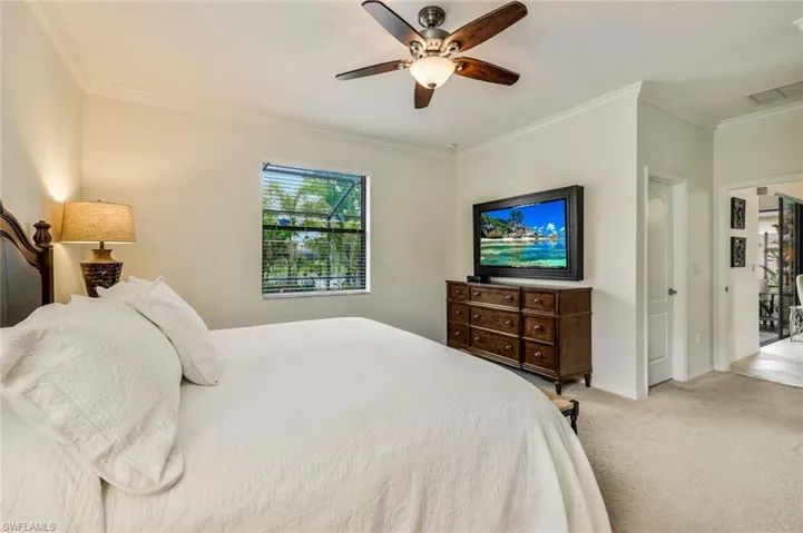 Carpeted bedroom featuring ornamental molding and ceiling fan