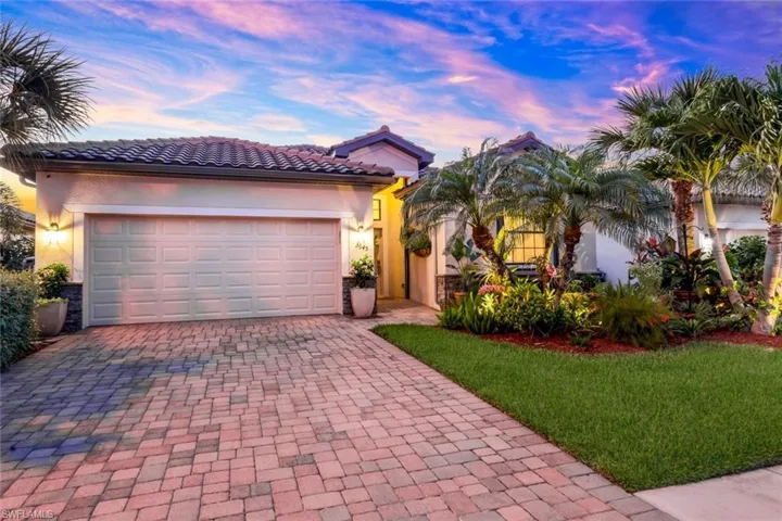 Mediterranean / spanish-style house with decorative driveway, stucco siding, a lawn, an attached garage, and a tiled roof