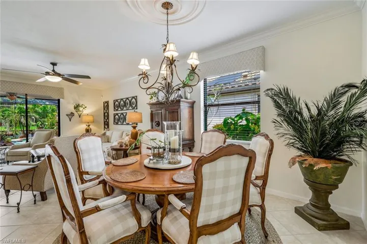 Dining space with crown molding, light tile patterned floors, ceiling fan, healthy amount of natural light, and a chandelier