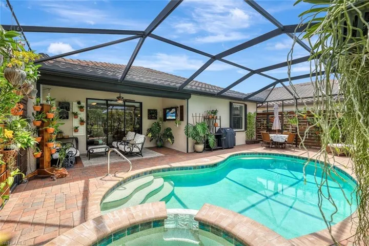 View of pool with a sunroom, a pool with connected hot tub, glass enclosure, a patio area, and area for grilling