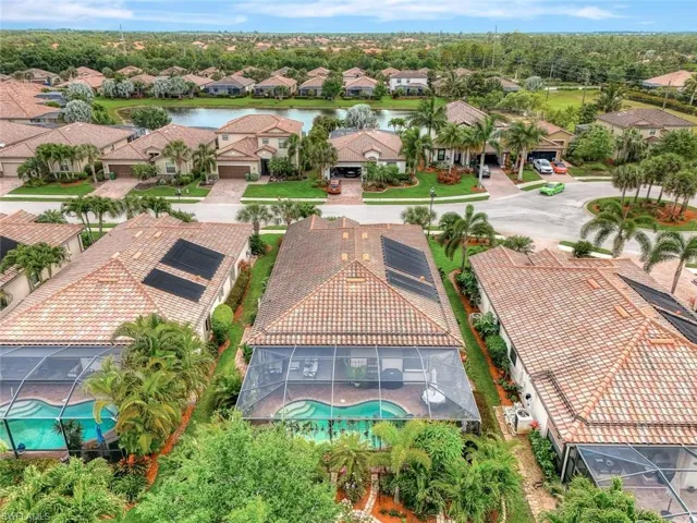 Aerial perspective of suburban area featuring a pool and a large body of water