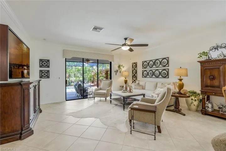 Living room with ornamental molding, a sunroom, light tile patterned floors, and a ceiling fan