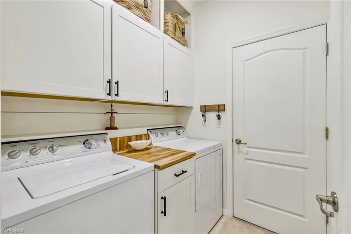 Laundry room with cabinet space, washing machine and clothes dryer, and light tile patterned floors