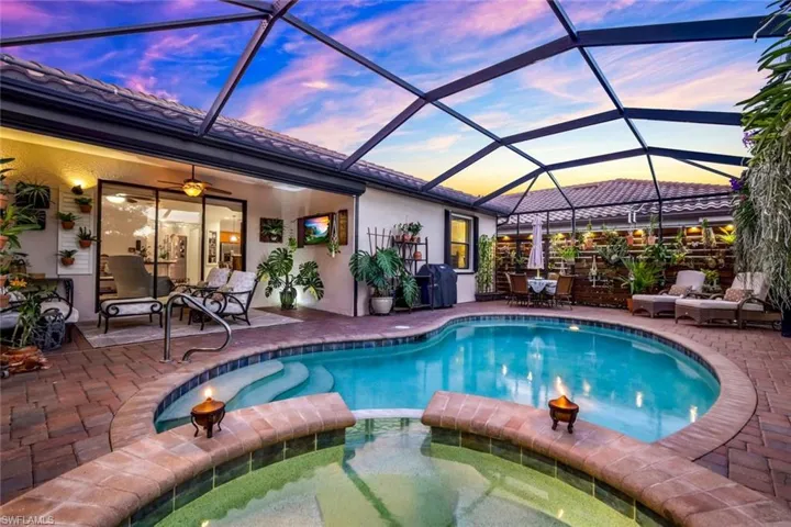 View of pool featuring a sunroom, a lanai, a pool with connected hot tub, and a patio