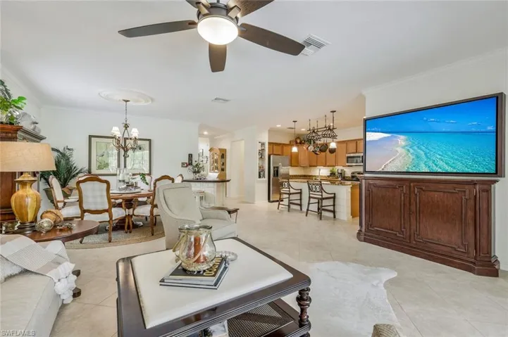 Living room featuring crown molding, a chandelier, ceiling fan, and light tile patterned floors