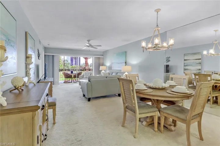 Dining area with a chandelier, light colored carpet, and a ceiling fan