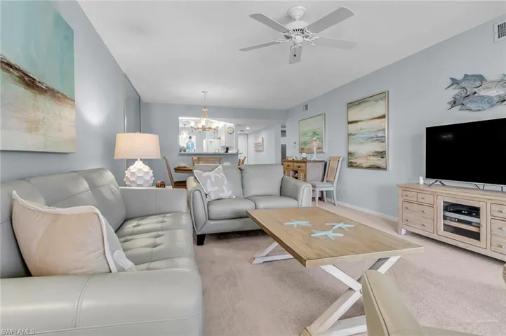 Living area with a chandelier, light colored carpet, ceiling fan, and baseboards
