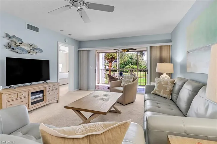 Carpeted living area featuring ceiling fan