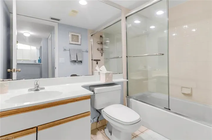 Bathroom featuring tile patterned flooring, recessed lighting, toilet, vanity, and enclosed tub / shower combo