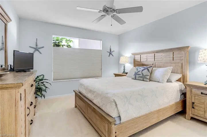 Bedroom with light carpet, a ceiling fan, and baseboards