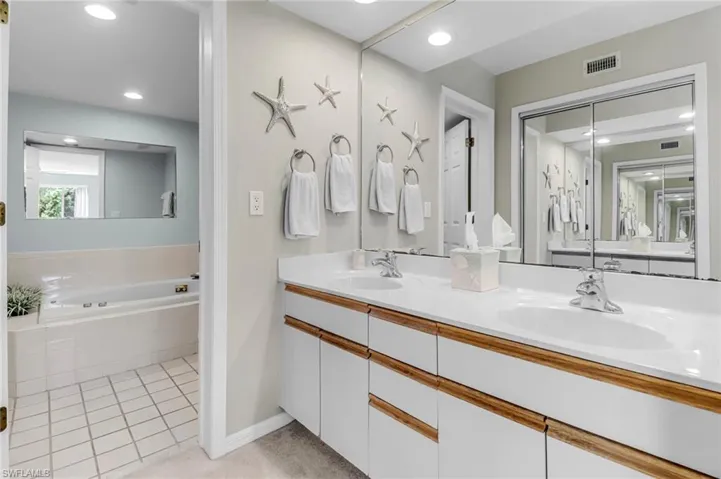 Full bath featuring a bath, double vanity, recessed lighting, tile patterned floors, and baseboards