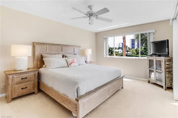 Bedroom with light carpet, baseboards, and a ceiling fan
