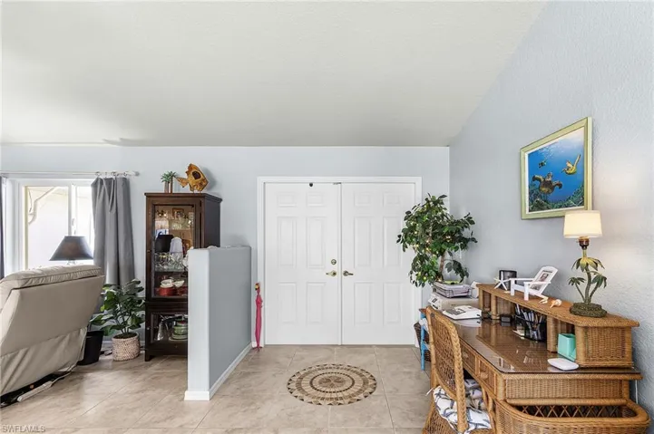 Entrance foyer featuring vaulted ceiling, light tile patterned floors, and a textured wall