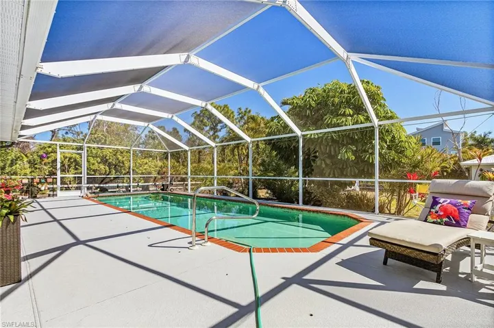 Swimming pool with a sunroom, a patio area, and glass enclosure