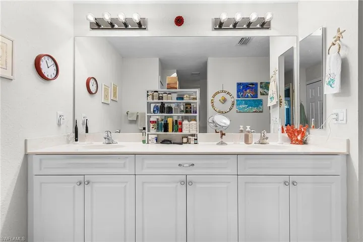 Full bathroom featuring double vanity and a textured wall