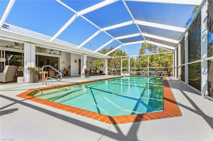 Outdoor pool with a patio, glass enclosure, and a sunroom