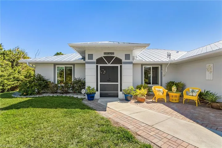 Doorway to property featuring a standing seam roof, a yard, and stucco siding