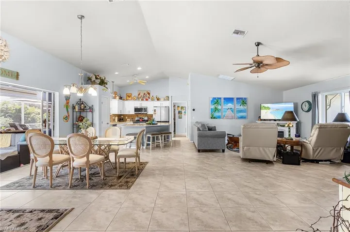 Dining room featuring plenty of natural light, a ceiling fan, vaulted ceiling, light tile patterned flooring, and suspended lighting