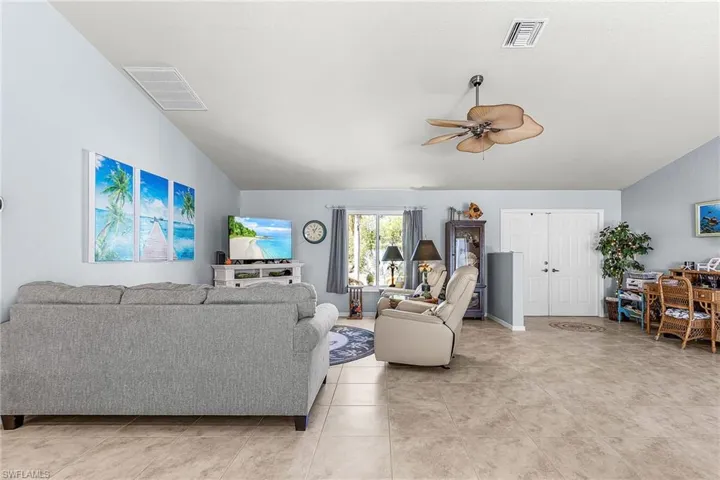 Living room with vaulted ceiling, a ceiling fan, and light tile patterned floors