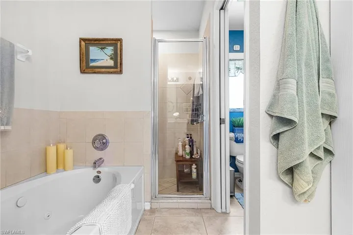 Bathroom featuring a shower stall, a tub with jets, and light tile patterned floors