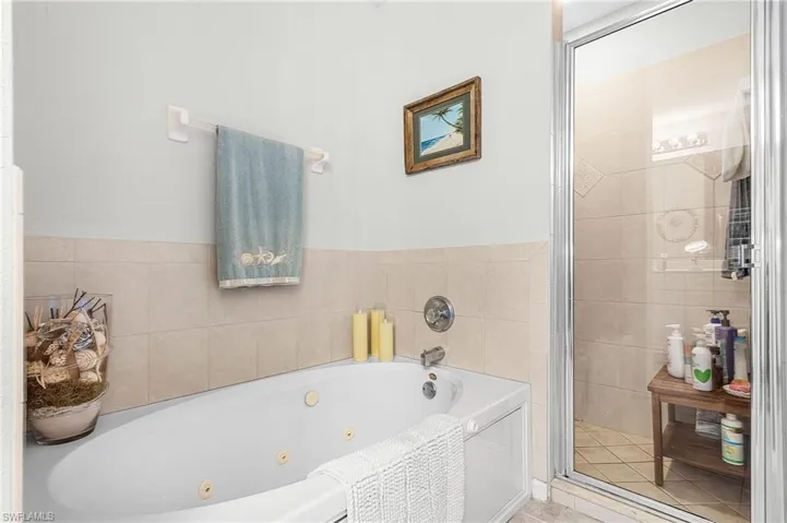 Bathroom featuring a shower stall and a tub with jets
