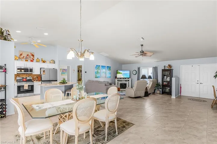 Dining room featuring ceiling fan, hanging lights, lofted ceiling, and light tile patterned floors