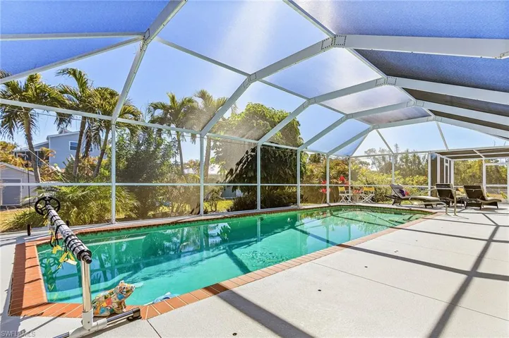 Outdoor pool featuring glass enclosure, a sunroom, and a patio