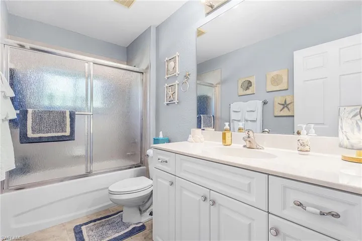 Full bathroom featuring vanity, a textured wall, shower / bath combination with glass door, and light tile patterned floors