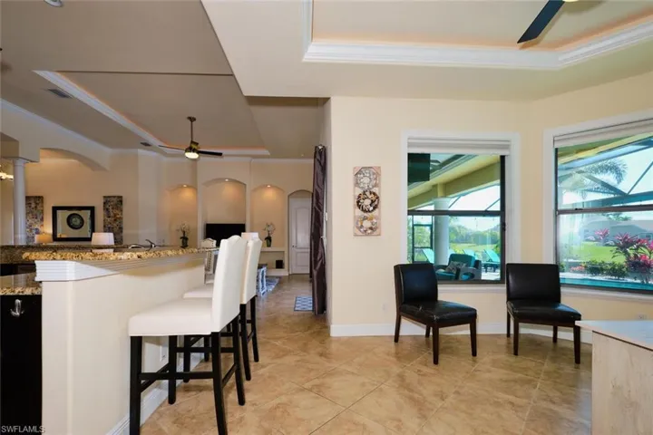 Kitchen featuring a tray ceiling, arched walkways, a ceiling fan, and crown molding