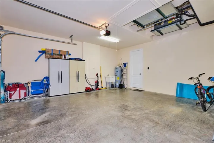 Garage featuring a sink, a garage door opener, and water heater