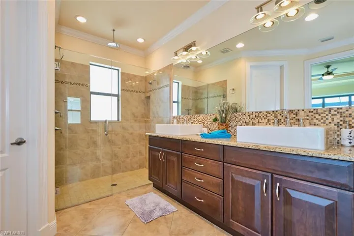Full bath featuring visible vents, ornamental molding, a stall shower, and a sink