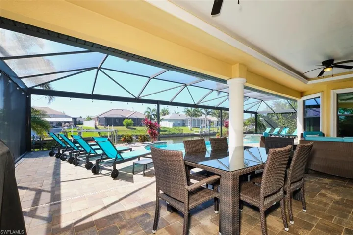 View of patio / terrace with glass enclosure, an outdoor pool, outdoor dining area, and a ceiling fan