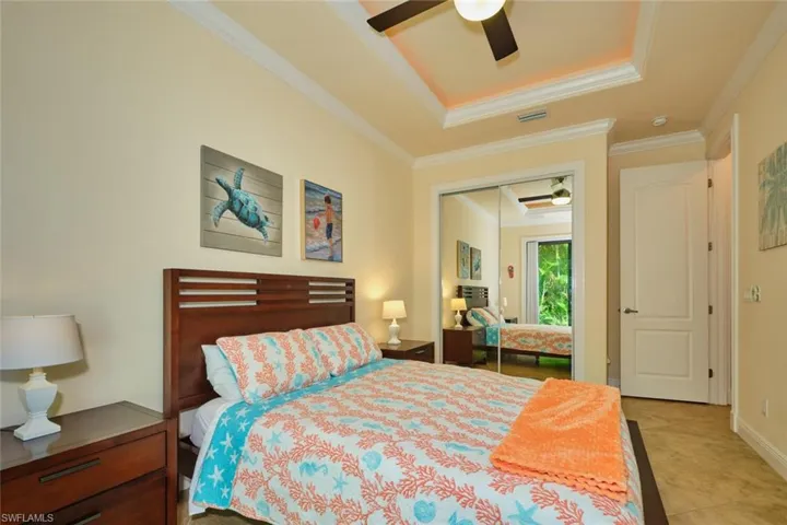 Bedroom featuring visible vents, ornamental molding, a tray ceiling, a closet, and ceiling fan