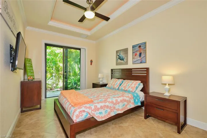 Bedroom with a tray ceiling, baseboards, crown molding, and access to outside