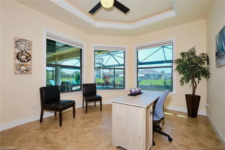 Office featuring a tray ceiling, a healthy amount of sunlight, ceiling fan, and a sunroom