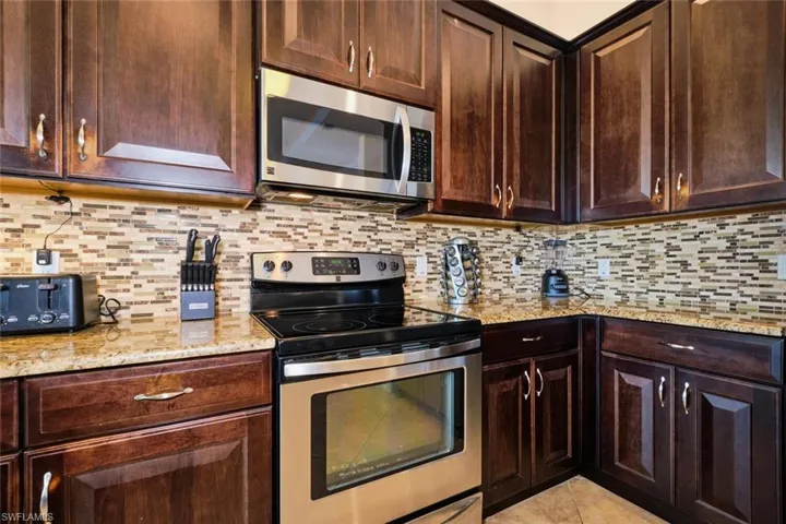 Kitchen featuring light stone counters, stainless steel appliances, and decorative backsplash