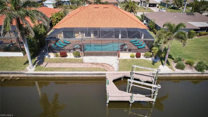 Dock area with a lanai, boat lift, a patio, and a water view