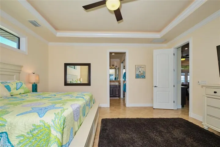 Bedroom with light tile patterned floors, baseboards, a raised ceiling, and crown molding