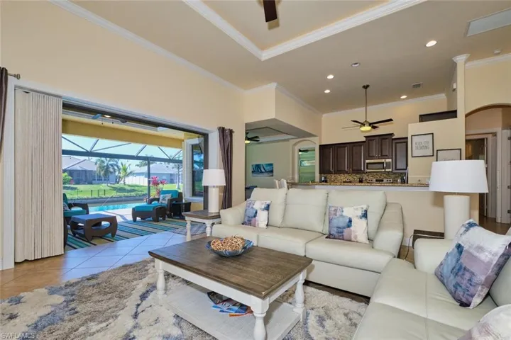 Living room featuring a ceiling fan, recessed lighting, light tile patterned flooring, crown molding, and a sunroom