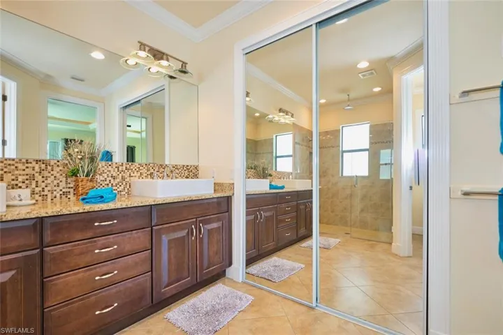 Bathroom featuring tile patterned floors, visible vents, ornamental molding, tasteful backsplash, and a shower stall