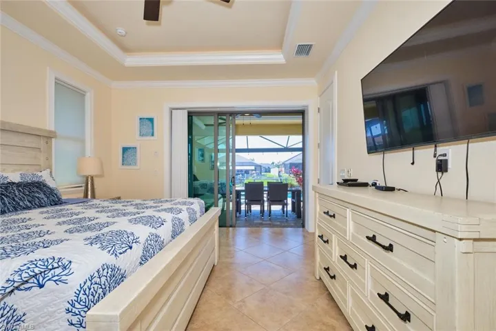 Bedroom with a tray ceiling, access to outside, visible vents, and ornamental molding